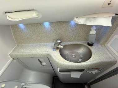 Uçak lavabosu musluk, sabun makinesi ve havlularla dolu. Hijyen, kompakt tesisler ve havayolu hizmetleri yolcu konforu ve havacılık seyahatini güvence altına alın