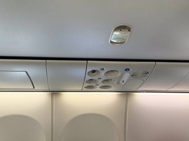 Yolcu koltuklarının üzerinde havalandırma delikleri, tabelalar ve kompartımanlar olan bir uçak kabini tavanı. Seyahat, havacılık ve konfor ve güvenlik için uçak iç mekanlarının teknik tasarımı