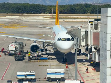 Geçit alanına ve yakınlardaki servis araçlarına bağlı seyyar merdivenleri olan bir havaalanı zemin görüntüsü. Altyapı, havacılık ve yolcu alımı hazırlıkları.