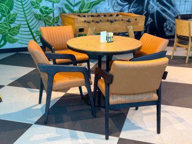 Langırt maçının yakınındaki bir kafede deri sandalyeli yuvarlak ahşap masa. Seyahat yaşam tarzı ve konukseverlik kültürünün bir parçası olarak gösterilen sosyalleşme, yemek ve boş zaman