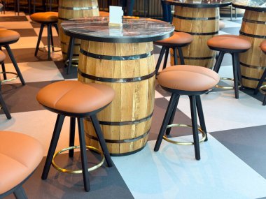 Kafe masası ahşap fıçıdan yapılmış, etrafında da yuvarlak yastıklı tabureler var. Yemek, konukseverlik ve sosyalleşme yoluyla dekorasyon, eğlence ve seyahat yaşam tarzının gösterimi