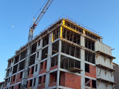 Vinç ve görünür iskeleti olan beton bina inşaat halinde. Modern bir konut projesi kapsamında mimari, mühendislik ve kentsel gelişim süreci devam ediyor