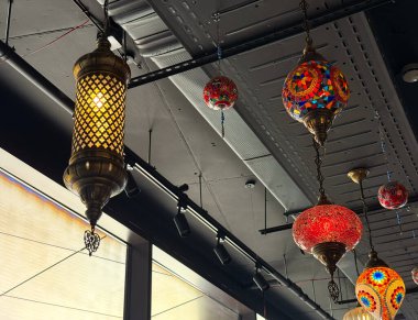 Asılma düzeninde kırmızı ve çok renkli camlı mozaik fenerler. Geleneksel zanaat, kültür sanatı ve miras aydınlatması konukseverliği ve canlı dekorasyonu simgeliyor.