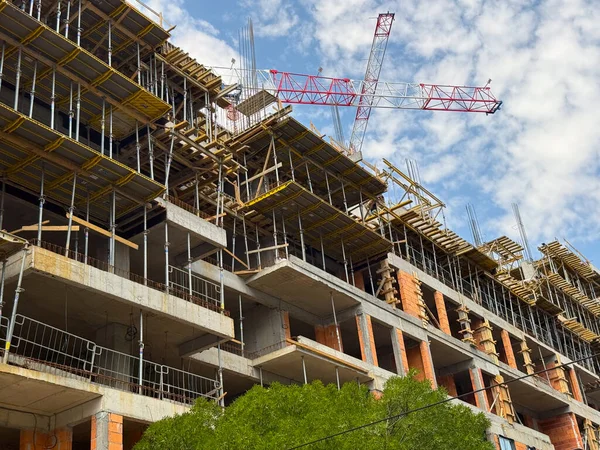 Üzerinde vinç olan bir inşaat alanında tuğla duvarlar ve iskeleler. Mimari büyüme, yapı mühendisliği ve kentsel genişleme.