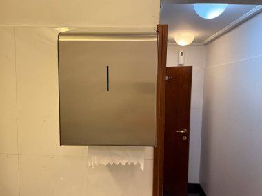 Tuvaletteki duvarda asılı kağıt havlu makinesi. Hijyen, temizlik ve sağlık hizmetleri modern tesisi ve günlük gerekliliği simgeliyor.