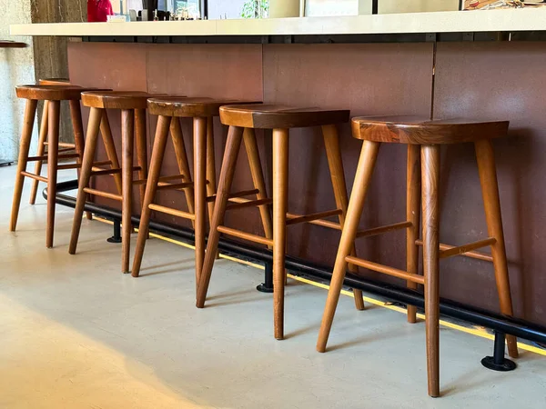 Ahşap bar tabureleri rahat iç kısımda tezgah boyunca düzgünce dizilmiş. Oturma, konukseverlik ve yaşam tarzı atmosferi mobilya tasarımı ve sosyal alan mobilyalarını ön plana çıkarıyor