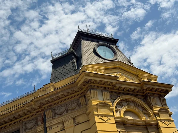 Yuvarlak saatli tarihi kule ve parlak gökyüzüne karşı detaylı mimari süslemeler. Şehir geleneğini, tasarımı ve mimari tarihini temsil eden miras, kültür ve kent simgesi