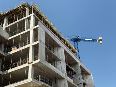 Üzerinde vinç olan bir inşaat alanında tuğla duvarlar ve iskeleler. Mimari büyüme, yapı mühendisliği ve kentsel genişleme.