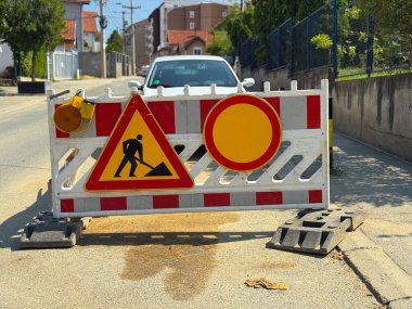 Yol inşaatı bariyeri ve trafik uyarı levhaları caddeyi güvenlik için kapatıyor. Önleme, ihtiyat ve kamu hizmetini temsil eden altyapı, düzenleme ve kentsel yönetim