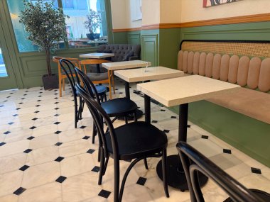 Masaları, sandalyeleri, döşemeleri ve yeşil duvarları olan boş bir kafe. Konukseverlik, modern tasarım ve konforlu sosyal ortamda günlük yaşam tarzı