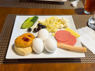 Haşlanmış yumurta, peynir, sosis, sebze ve hamur işi ile kahvaltı tabağı. Otel yemek servisinde besin, gıda kültürü ve yaşam tarzı