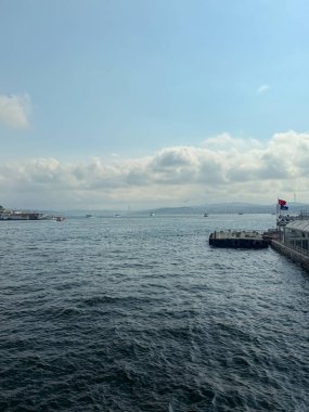 Tekneleri, köprüsü ve bulutlu gökyüzü olan Boğaz Rıhtımı manzarası. Deniz taşımacılığı, seyahat ve manzaralı şehir manzarası