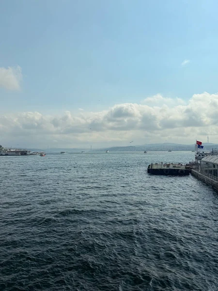 Tekneleri, köprüsü ve bulutlu gökyüzü olan Boğaz Rıhtımı manzarası. Deniz taşımacılığı, seyahat ve manzaralı şehir manzarası