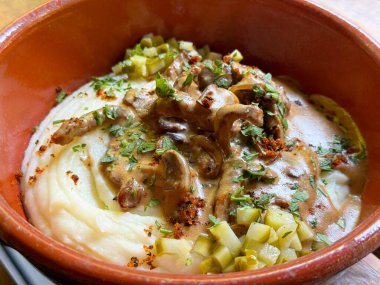 Geleneksel et ve patates püresi kilden bir kasede servis edilir. Ev yapımı mutfağın rahatlığı, tadı ve kültürel zenginliği.