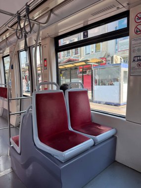 Toplu taşımacılıkta pencere kenarındaki tramvay koltukları. Kentsel hareketlilik, günlük seyahat ve yolcu yaşam tarzı altyapıyı, seyahat hizmetini ve şehir bağlantısını sembolize ediyor.