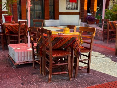 Tahta sandalyeler ve açık kafede desenli kumaşlı masa. Gelenek, kültür ve kırsal konukseverlik sanatsal zanaat, dekorasyon ve yaşam tarzı atmosferini gösteriyor