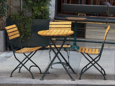 Açık kafe sandalyeleri ve tahta çıtçıtlı bir masa. Kentsel yaşam tarzı, rahatlama ve rahatlık.