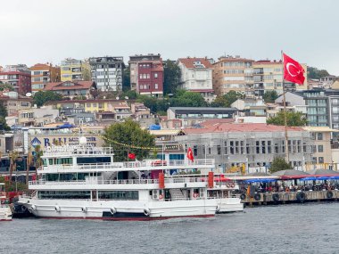 İstanbul 'daki iskelede Türk bayrağı taşıyan yolcu feribotu. Kentsel yaşam, ulaşım ve Boğaz deniz kültürü