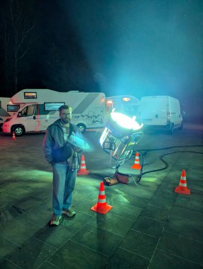 Geceleri açık hava sinemasında sahne ışıkları yanında duran bir adam. Sinematografideki film üretimi, teknoloji ve sanatsal atmosfer
