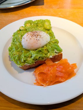 Avokado tostu, haşlanmış yumurta ve somon. Sağlıklı yaşam tarzı, dengeli diyet ve besleyici gurme yemeği.