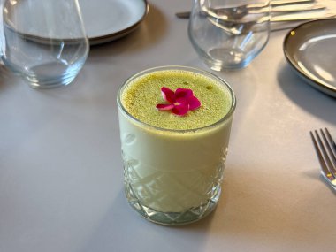 Bir bardak yeşil kibrit, yanında da yenilebilir çiçek. Kafe ortamında içecek, garnitür ve modern sunum tazeleniyor