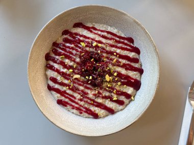 Masada bir kase kremalı puding, ahududu sosu ve ezilmiş şam fıstığı var. Tatlı, tatlı yemek ve modern yemek konseptinde yaratıcılık.