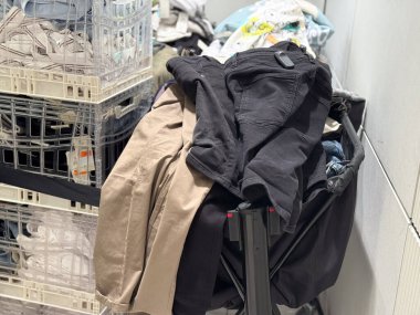 Perakende depolama arabasındaki katlanmış ve istiflenmiş pantolonlar moda malzemelerini gösteriyor. Moda endüstrisinde tüketici talebi, ticaret, tekstil ticareti ve mevsimsel organizasyon