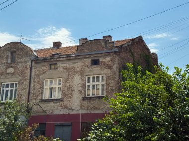 Belgrad 'daki kiremit çatılı eski tuğla ev, eskimiş ön cephe ve yaz gökyüzünün altında yeşillik. Mimari miras, kentsel gelenek, tarih, nostalji, toplum, Sırbistan 'ın kültürel kimliği ve yerleşim ortamı