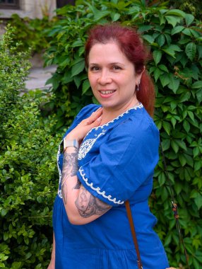 Gülümseyen bir kadın göğsüne kadar yükselmiş ve kolunda dövmesi olan yaprakların yanında poz veriyor. Bireyselliğin, cazibenin ve kendine güvenin portresi yaşam tarzıyla ifade edilir.