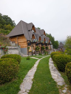 Kesilmiş çalılar ve taş patikalarla çevrili sivri çatılı küçük ahşap kulübeler. Sırbistan 'da turizm ve dağ konaklama