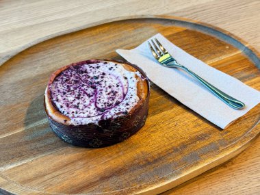 Tahta tepsiye çatal ve peçeteyle yerleştirilmiş çilekli cheesecake. Tatlılık, hoşgörü, yaşam tarzı ve tatlı kültürü ve mutfak sunumu ile gastronomi