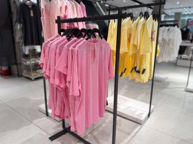 Pembe ve sarı tişörtler moda mağazalarında raflarda düzenlenir. Çağdaş tekstil endüstrisinde alışveriş, tüketici yaşam tarzı, mevsimsel renk eğilimi ve ticaret