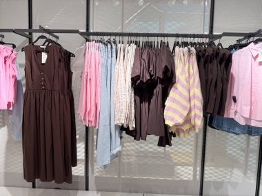 Bir perakende mağazasında elbise, kazak ve gömlekler yumuşak ve koyu tonlarda sergilenir. Moda ticareti, tüketici yaşam tarzı, tekstil endüstrisi ve kentsel ticarette mevsimsel alışveriş kültürü