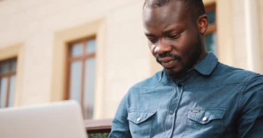 Afro-Amerikan bussinesman bankta oturur ve onun laptop İnşaat