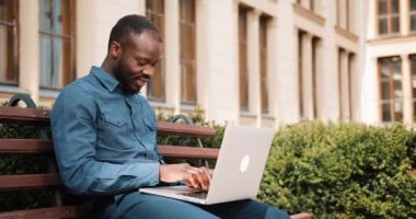 Afro-Amerikan bussinesman bankta oturur ve onun laptop İnşaat