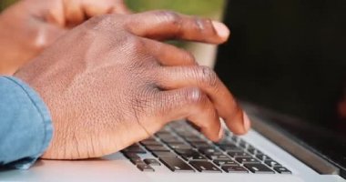 Genç siyah adam elinde kapatın. O bir gömlek giymiş ve onun laptop klavyeden yazarak. Serbest bir iş kavramı. Gerçek zamanlı yakın çekim yukarı kilitli