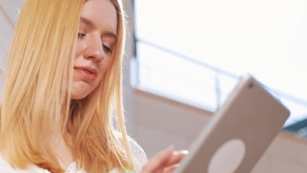 Jolie jeune femme blonde utilisant un ordinateur tablette à l'extérieur dans la rue. Femme souriante, tapant sur l'écran tactile, regardant des vidéos, des nouvelles — Video