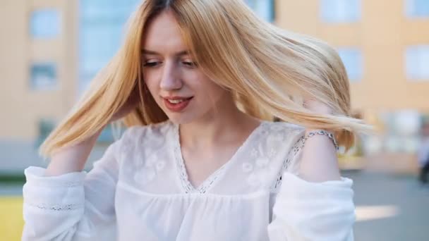 Wind bläst Frauen blonde Haare, während sie draußen steht — Stockvideo