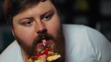 Sakallı şişman adam bira ile masada oturan ve Mısır-televizyon önce pizza yiyor