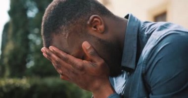 Üzgün ve depresyonda genç siyah Afrika işadamı oturur sokakta çağırdıktan sonra yorgun. Kötü haber, hayal kırıklığı, hastalık kavramı