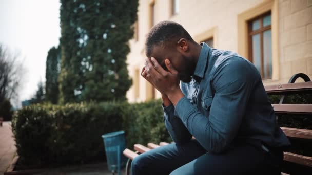 Üzgün ve depresyonda genç siyah Afrika işadamı oturur sokakta çağırdıktan sonra yorgun. Kötü haber, hayal kırıklığı, hastalık kavramı — Stok video