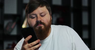 Şişman adam Tv ve türleri bir şey onun smartphone içinde izliyor. Eve yemek siparişleri. Yetersiz beslenme, gıda dağıtım, geri kalan kavramı