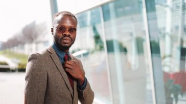 Güneş gözlüğü businesman ile yakışıklı African American cam bina önce sokakta moder elbiseli teşkil etmektedir. Başarılı iş kavramı