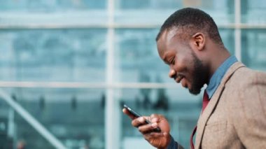 Afrika kökenli Amerikalı adam iş merkezi yakınında sokakta yürürken onun smartphone içinde bir ileti türleri. Başarı, iletişim ve iş kavramı