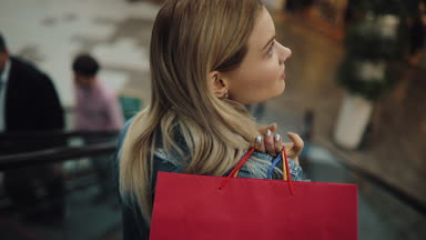 Genç sarışın kadın Kot ceket gülümsüyor alışveriş merkezi hareketli merdiven iniyor