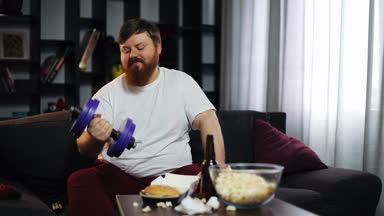 Şişko yeme fast food, içki bira ve halter eğitim yapıyor. O evde Tv. kavramı yetersiz beslenme, spor, obezite önünde kanepede oturuyor