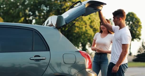 Das glückliche Paar ist mit dem Auto in den Urlaub gefahren. Gepäck aus dem Auto holen — Stockvideo