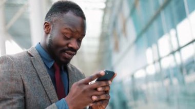 Genç Afrika Smartphone akıllı telefon mutlu gülümseyerek kullanarak office center yakışıklı genç işadamı yakınındaki şehirde app kullanarak Americanman.