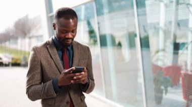 Ofis Binası yakınındaki bir smartphone ayakta kullanarak mutlu Afrika kökenli Amerikalı iş adamı. İş, insanlar, iletişim, teknoloji, eğlence ve yaşam tarzı kavramı