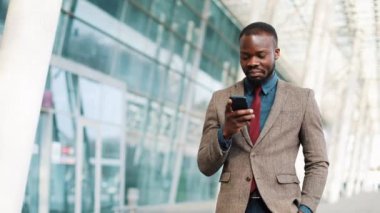 kaçık Amerikalı işadamı ofis binası yakınında yürüyüş bir smartphone kullanarak. İş, insanlar, iletişim, teknoloji, eğlence ve yaşam tarzı kavramı